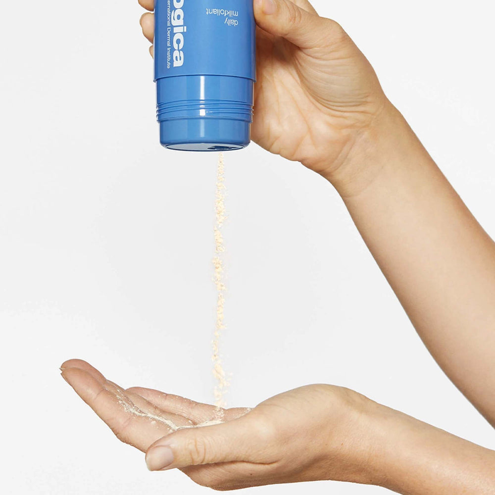 Hand holding a daily milkfoliant product with visible powder on the palm against a light background